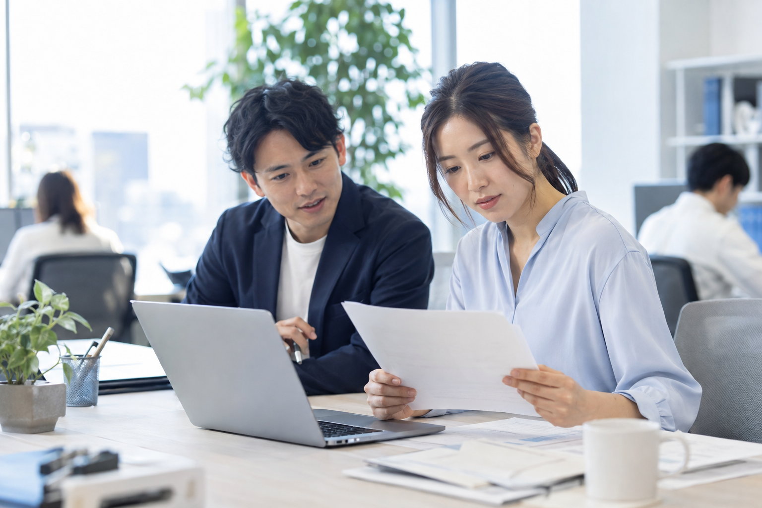 書類とPCの内容を照合する事務担当者のイメージ